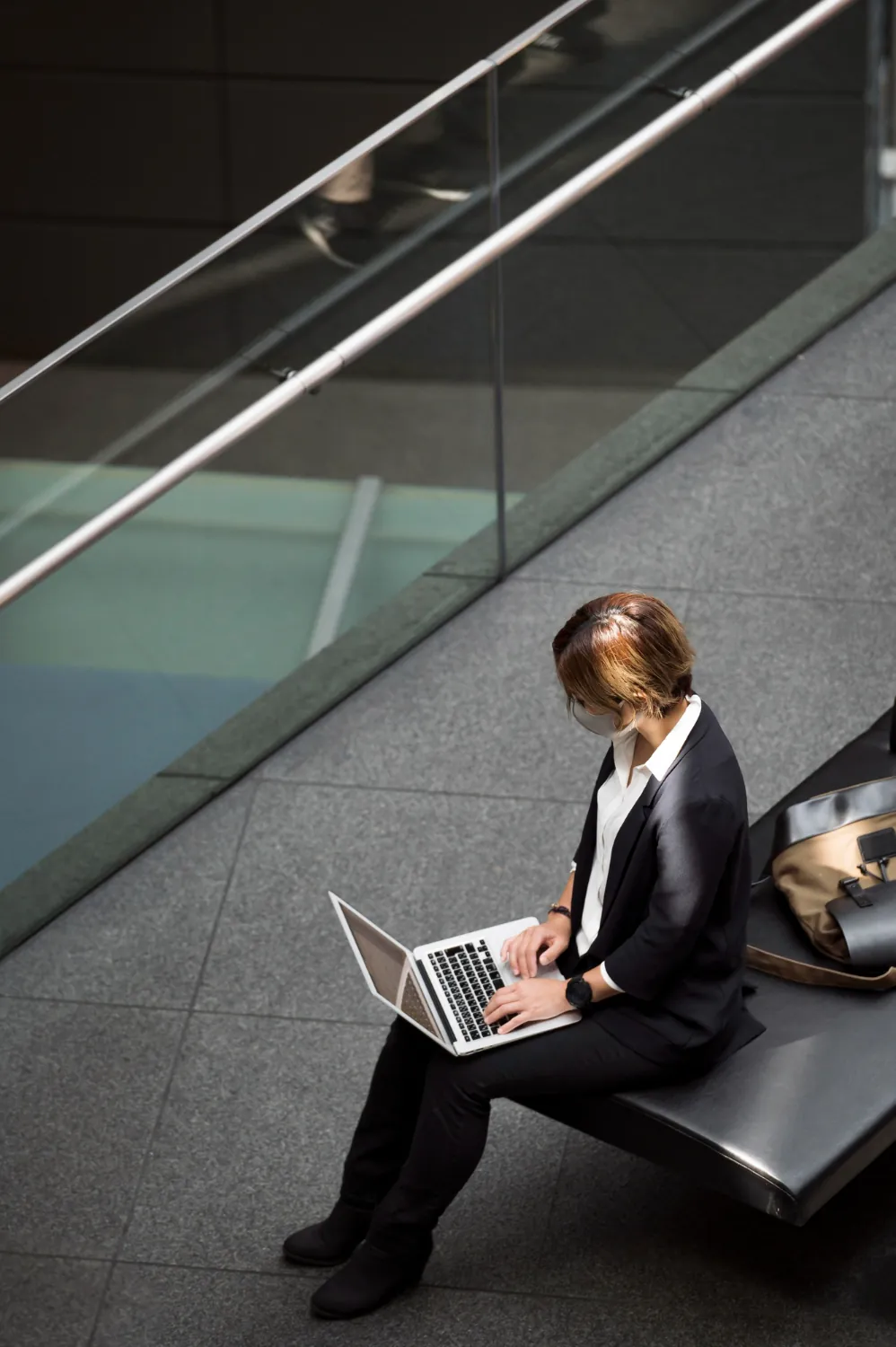 Corporate women working on a laptop in a modern mall setting.
