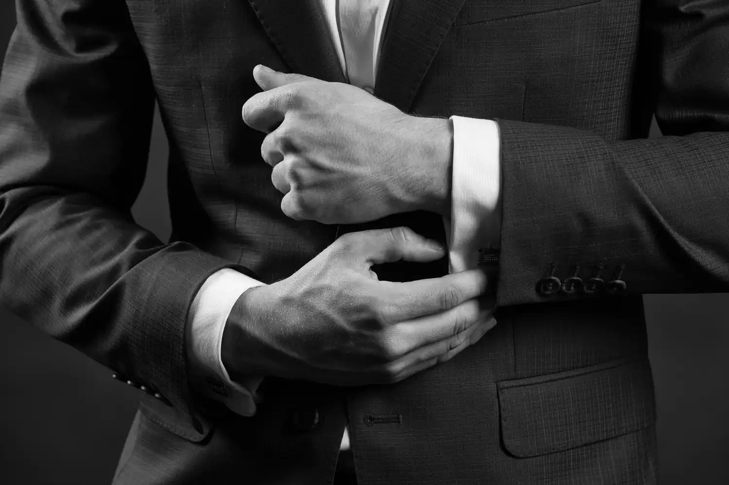 A person in business suits adjust their jackets in a black-and-white setting. The image represents Dot&’s Executive Intelligence, Data Advisory, and Cybersecurity services in the GCC